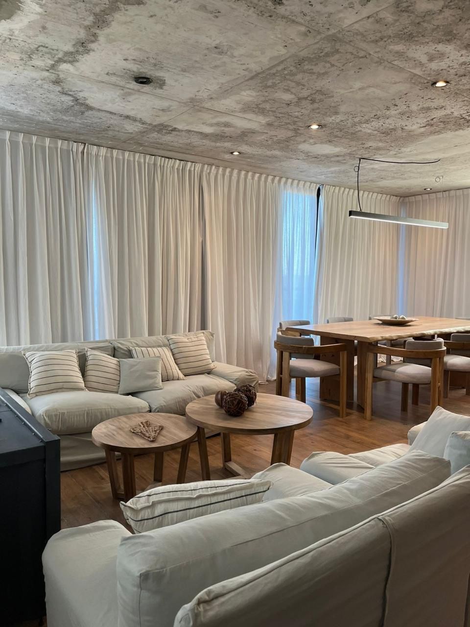 Estar del nivel principal, con cielorraso de hormigón y cortinas claras, fotografía de obra
