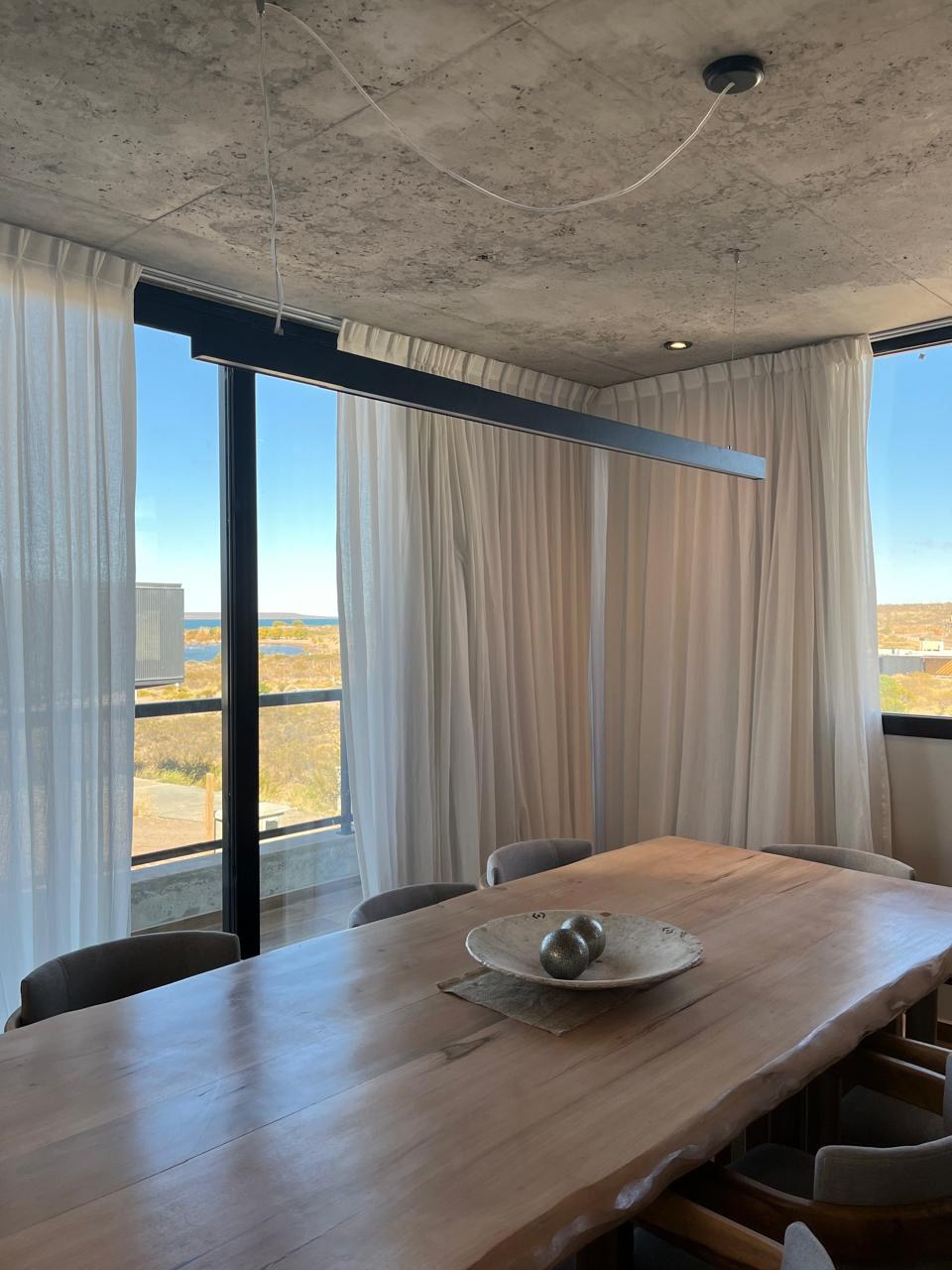 Comedor junto al ventanal, con mesa de madera maciza, fotografía de obra
